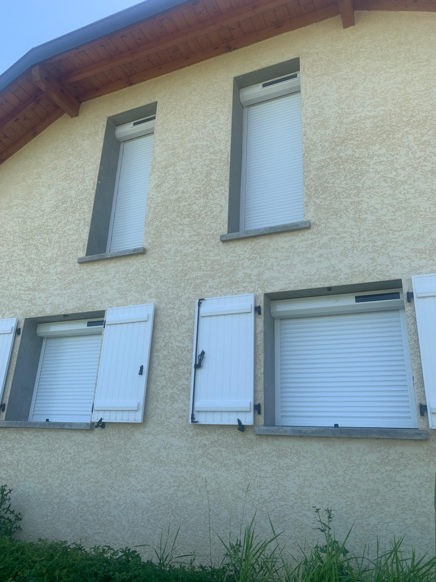 Façade avec volets roulants posés sur plusieurs fenêtres
